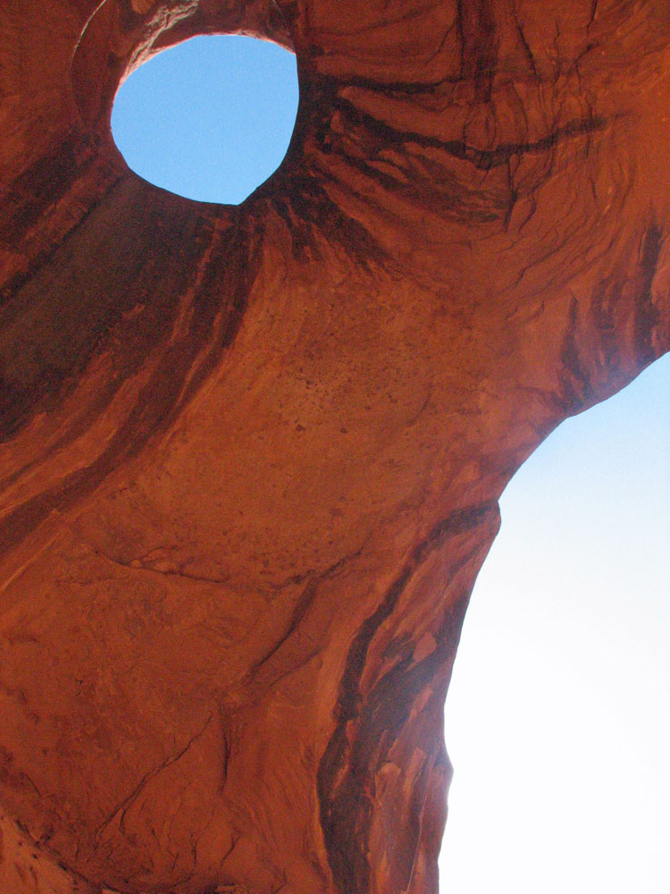 Photo of hole in rock arch against the blue sky