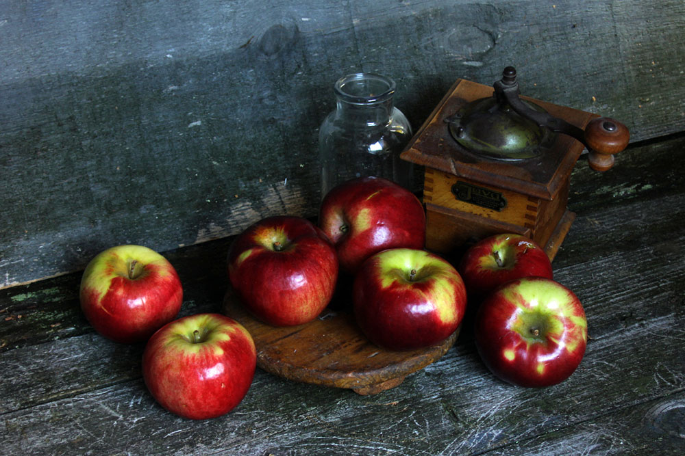 Photo of apples, glass bottle, antique coffee grinder
