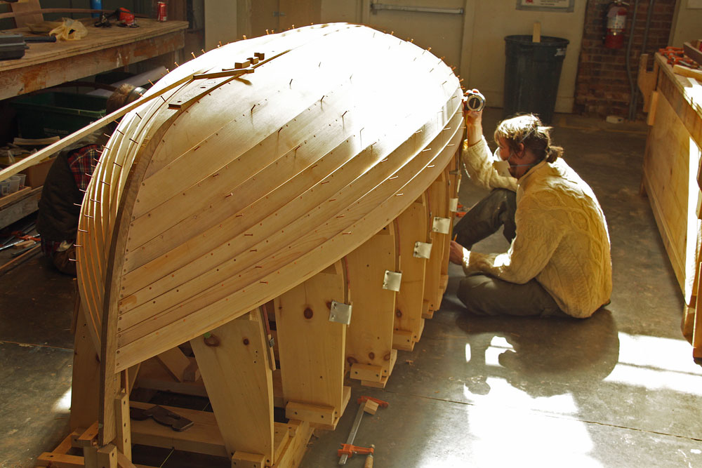 Photo of boat builder working on small wooden boat